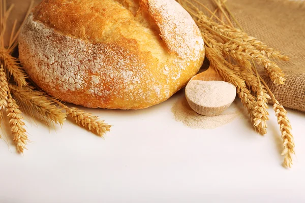 Pan fresco con trigo y cuchara de madera de harina aislada sobre blanco — Foto de Stock