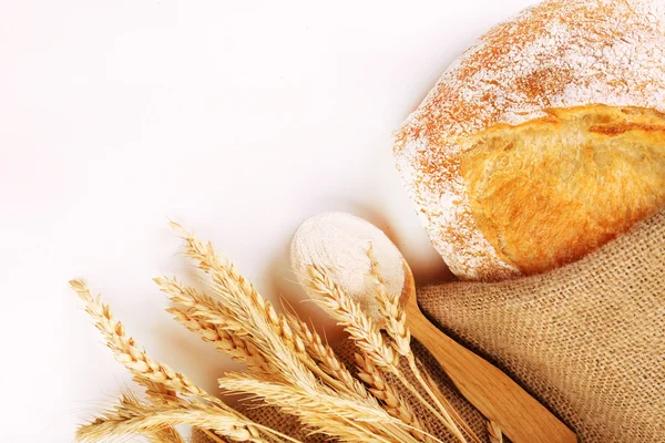 Pan fresco con trigo y cuchara de madera de harina aislada sobre blanco — Foto de Stock