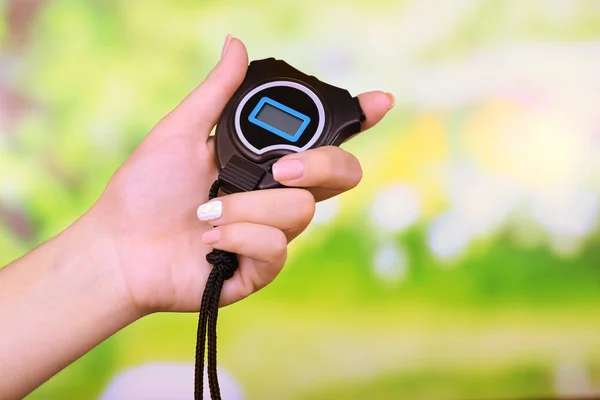 Electronic sport timer in  female hand on bright blurred background