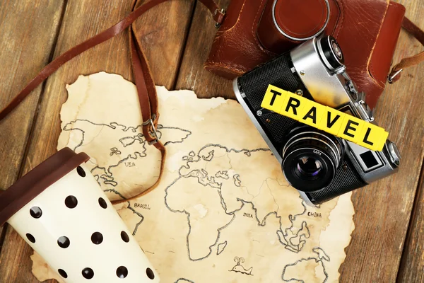 Retro camera on world map with word Travel on wooden table background — Stock Photo, Image