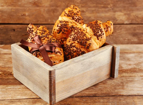 Croissants frescos e saborosos com chocolate em fundo de madeira — Fotografia de Stock