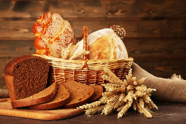 Различные хлеба с ушами в корзине на деревянном фоне — стоковое фото