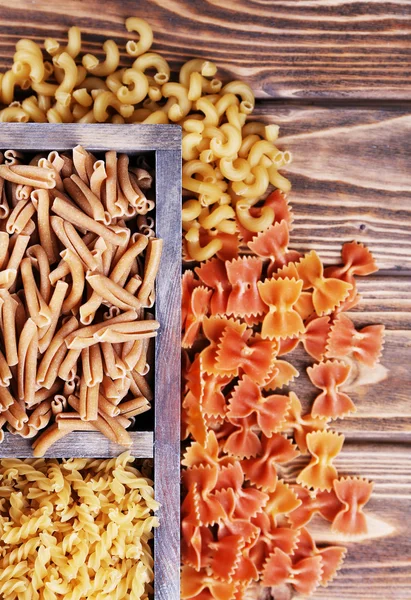 Different types of pasta in box on wooden background — Stock Photo, Image