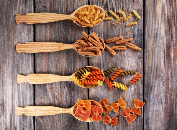 Различные виды макарон в ложках на деревянном фоне — стоковое фото