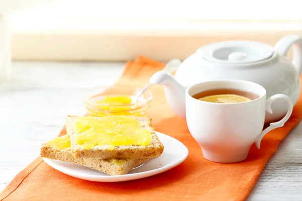 Toasts with honey on plate and cup of tea on light background — Stock Photo, Image