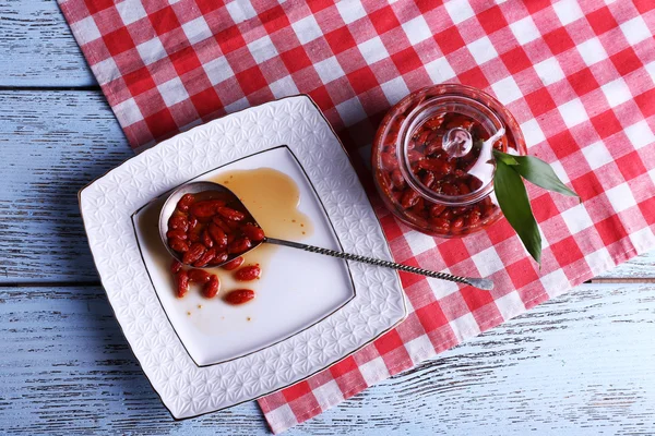 Goji μούρων μαρμελάδα στο κουτάλι στο πιάτο με το βάζο στο τραπέζι σε κοντινό πλάνο — Φωτογραφία Αρχείου