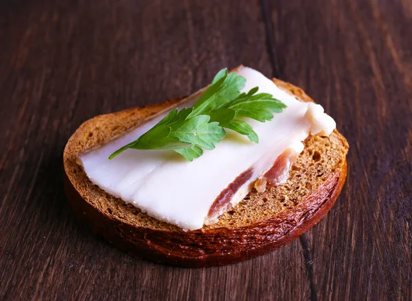 Сэндвич с салом и петрушкой на деревянном фоне — стоковое фото
