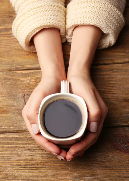 Female hands holding cup of coffee on wooden background — Stock Photo, Image