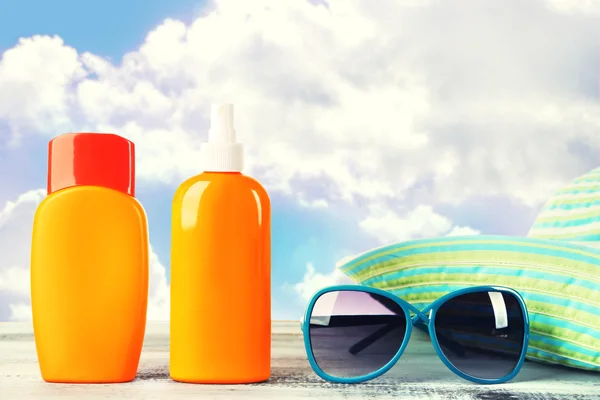 Botellas de crema bronceadora con gafas de sol y sombrero sobre mesa aislada en blanco —  Fotos de Stock