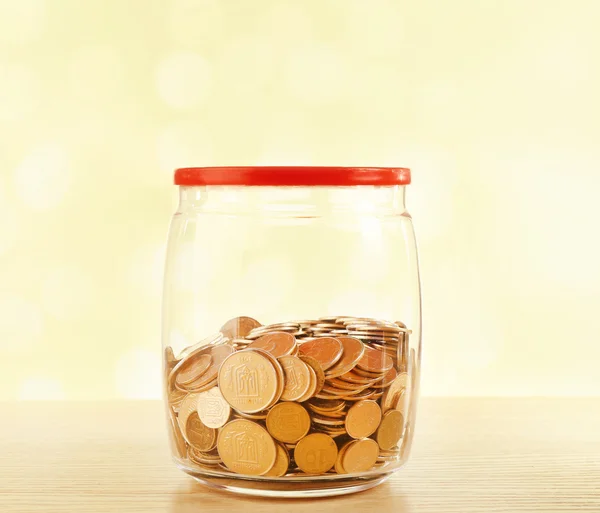 Gold coins in glass bottle on bright blurred background — Stock Photo, Image