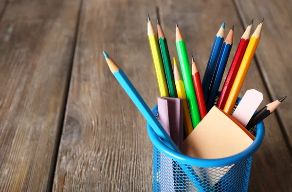 Crayons colorés en porte-métal avec des notes collantes sur fond de planches de bois — Photo