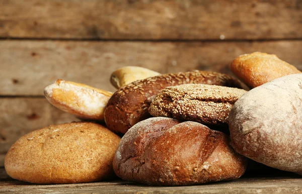 Different fresh bread on old wooden table — Stock Photo, Image