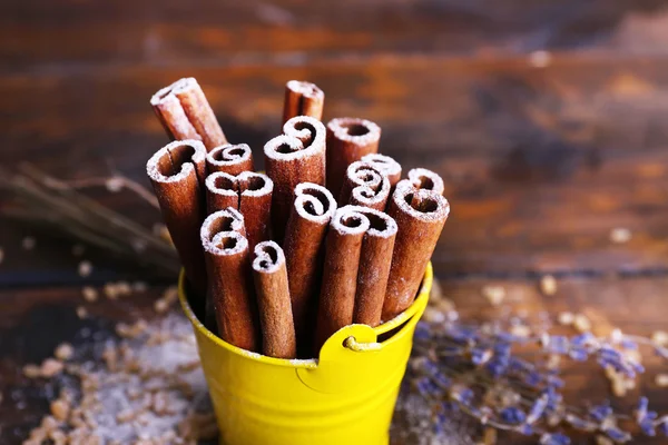 Varas de canela com açúcar e lavanda sobre fundo de mesa de madeira — Fotografia de Stock