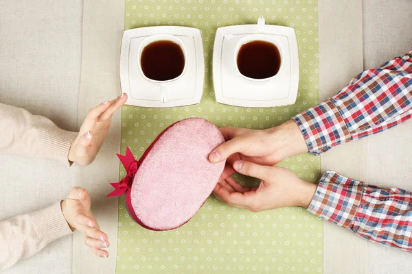 Mani femminili e maschili con tazze di tè e confezione regalo, primo piano — Foto Stock