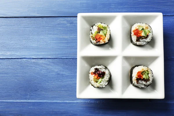 Rollos de sushi vegetal en plato sobre fondo de madera de color —  Fotos de Stock