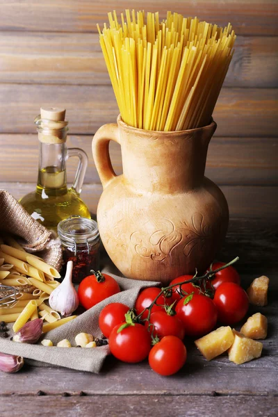 Pâtes aux tomates cerises et autres ingrédients sur fond de table et de planches en bois — Photo