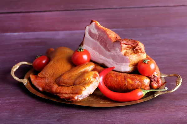 Assortment of smoked meat on metal tray on color wooden table background — Stock Photo, Image