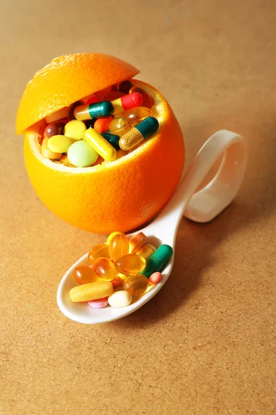 Pomarańczowe owoce i kolorowe tabletki, na tle drewniane — Zdjęcie stockowe