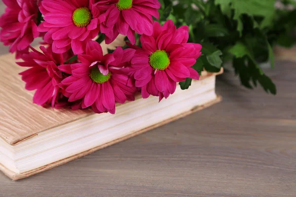 Beautiful flowers with book on wooden table, closeup — Stock Photo, Image