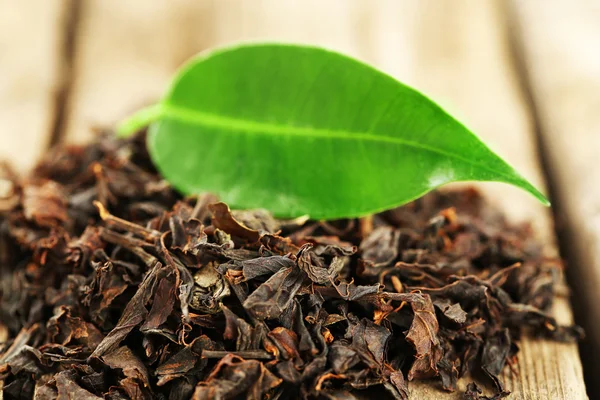 Té negro con hoja sobre mesa de madera vieja —  Fotos de Stock