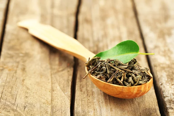 Groene thee met blad in lepel op oude houten tafel — Stockfoto