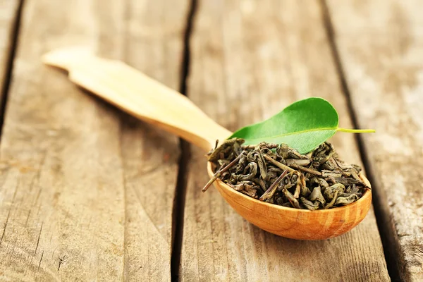 Té verde con hoja en cuchara sobre mesa de madera vieja — Foto de Stock