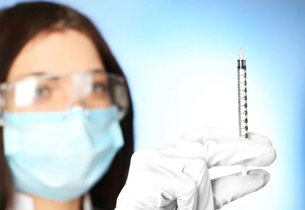 Ampola e seringa nas mãos do médico sobre fundo azul — Fotografia de Stock