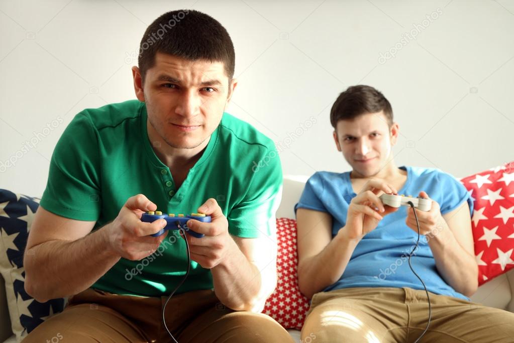 Two handsome young men playing video games in room