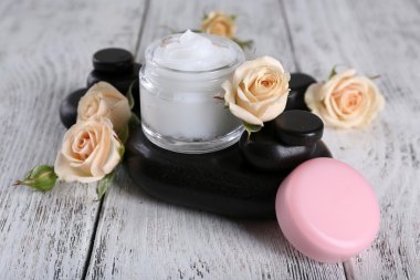 Çiçek ve spa taşlar ahşap arka plan üzerinde kozmetik krem