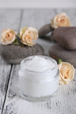 Çiçek ve spa taşlar ahşap arka plan üzerinde kozmetik krem