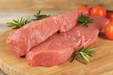 Biberiye ve domates ahşap arka plan üzerinde kesme tahtası üzerinde ham sığır eti biftek