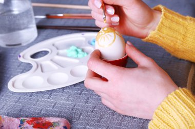 Renkli masa örtüsü arka plan üzerinde eller tarafından Paskalya yumurta boyama