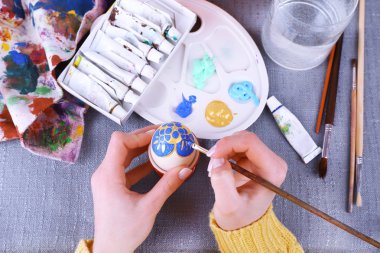 Renkli masa örtüsü arka plan üzerinde eller tarafından Paskalya yumurta boyama