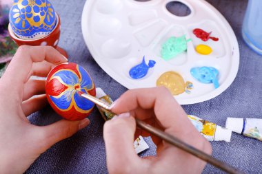 Renkli masa örtüsü arka plan üzerinde eller tarafından Paskalya yumurta boyama