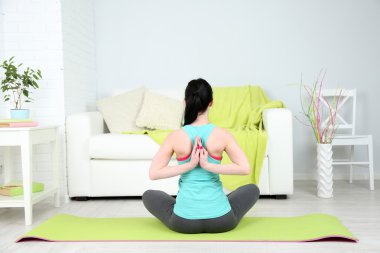 Evde yoga yapan genç bir kadın.