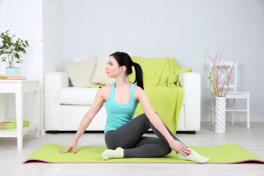 Evde yoga yapan genç bir kadın.