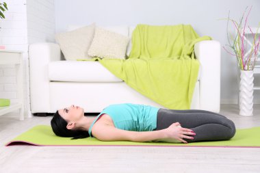 Evde yoga yapan genç bir kadın.