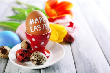 Paskalya yumurtaları sahipleri ve Lale çiçek ahşap arka plan üzerinde