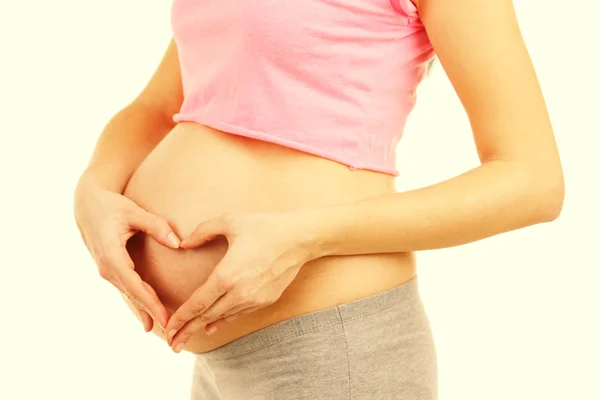 Schöne junge schwangere Frau berührt ihren Bauch auf hellem Hintergrund — Stockfoto