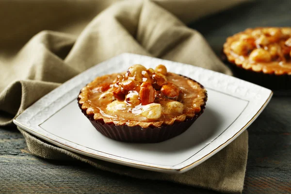 Mini torte con noci su tovagliolo su sfondo di legno — Foto Stock