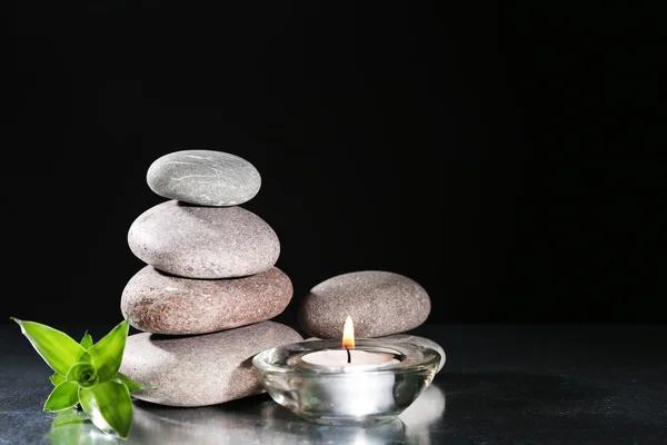 Mooie compositie met spa stenen en kaars op tafel op donkere achtergrond — Stockfoto