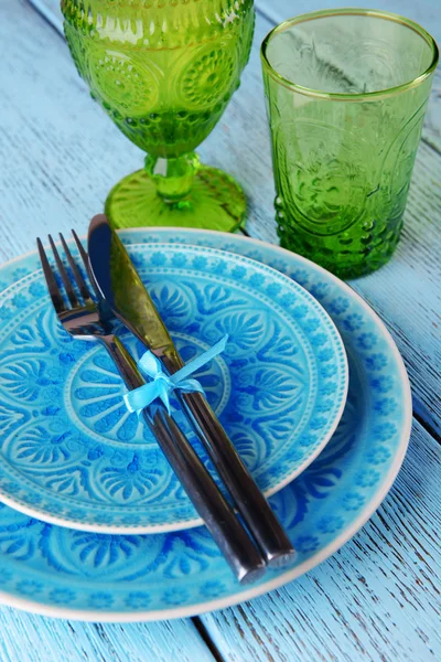 Assiette colorée vide, verres et argenterie sur table en bois — Photo