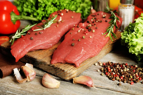Raw beef steak with spices and greens on table close up — Stock Photo, Image