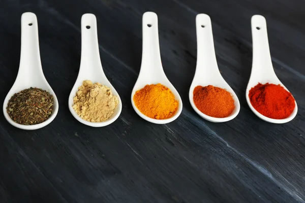 Different kinds of spices in spoons on wooden background — Stock Photo, Image
