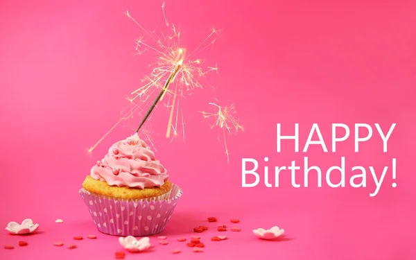 Cupcake with sparkler on pink background — Stock Photo, Image