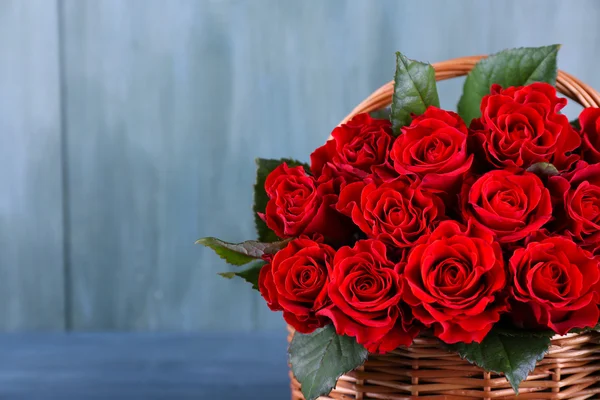 Boeket van rode rozen in mand op houten achtergrond — Stockfoto