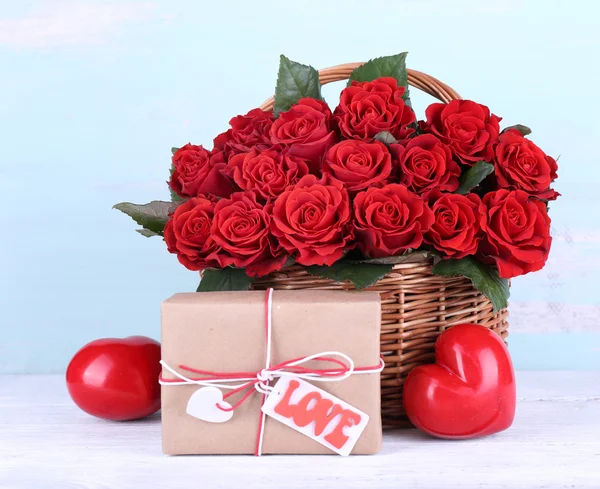 Ramo de rosas rojas en cesta con caja de regalo sobre fondo de madera — Foto de Stock