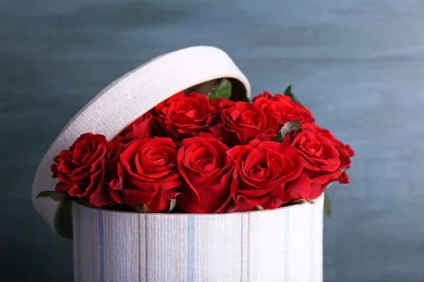 Μπουκέτο από κόκκινα τριαντάφυλλα σε κουτί κλωστοϋφαντουργίας σε ξύλινα φόντο — Φωτογραφία Αρχείου