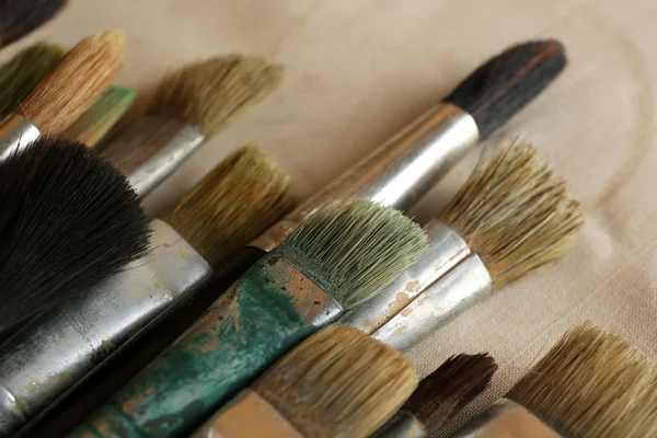 Different paintbrushes on fabric background — Stock Photo, Image