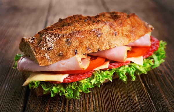 Vers en smakelijk sandwich met ham en groenten op houten achtergrond — Stockfoto